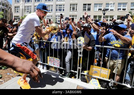 12 juin 2018 - Oakland, CA, États-Unis - les fans regardent de plus près alors que Stephen Curry des Golden State Warriors remporte le trophée du championnat Larry O'Brien NBA après être descendu d'un bus à impériale lors de la parade de championnat de l'équipe dans le centre-ville d'Oakland, Calif, le mardi 12 juin 2018. (Crédit image : © Ray Chavez/TNS via ZUMA Wire) Banque D'Images