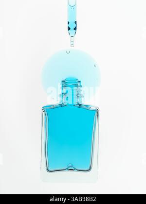Gros plan de gouttelettes de liquide bleu tombant dans un flacon cosmétique ouvert à l'aide d'une pipette. Cette photo minimaliste met l'accent sur la clarté et la précision Banque D'Images