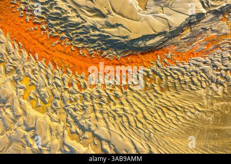 Capture aérienne de motifs de sable présentant des couleurs vives et des motifs complexes. L'interaction de la lumière et de l'ombre met en évidence les textures et la dynamique l Banque D'Images