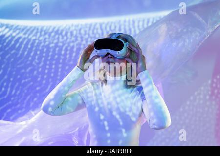 Une femme asiatique âgée s'engage avec la technologie dans la métaverse, portant un casque de réalité virtuelle. Immergée dans un monde numérique, elle expérimente innov Banque D'Images