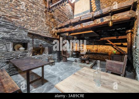 Cuisine traditionnelle aux murs en pierre dans une ancienne maison de campagne à Lugo, en Espagne, avec poutres apparentes, mobilier vintage et décor rural. Banque D'Images