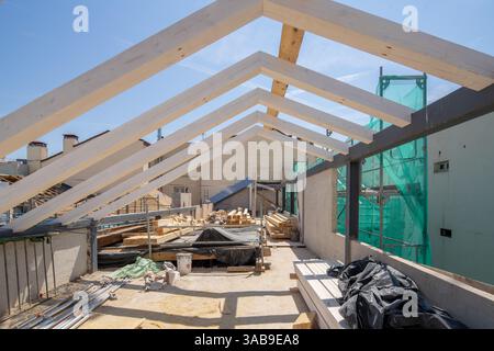 Un chantier de construction avec des poutres en bois apparentes et des matériaux dispersés. Le ciel dégagé améliore le cadre ouvert et inachevé, suggérant des progrès Banque D'Images