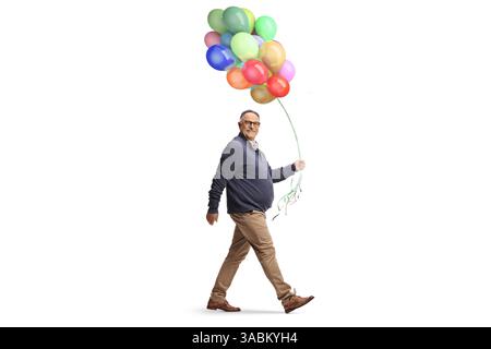 Homme mûr marchant avec un tas de ballons colorés isolés sur fond blanc Banque D'Images