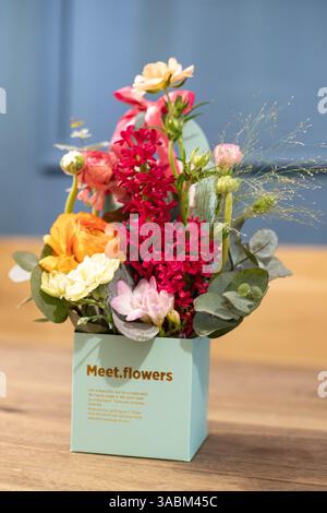 Bouquet de fleurs artificielles multicolores, rose, jaune, blanc dans un sac en papier bleu, ravit les yeux et décore magnifiquement la pièce Banque D'Images