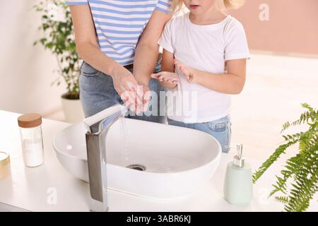 Mère et fille se lavant les mains à l'intérieur, gros plan Banque D'Images