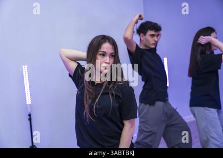 Groupe de jeunes danseurs pratiquant une chorégraphie moderne dans un studio de danse éclairé par des néons violets Banque D'Images