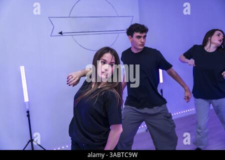 Groupe de jeunes danseurs pratiquant une chorégraphie moderne dans un studio de danse avec des néons Banque D'Images