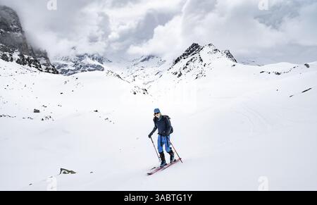 Paysage de montagne d'hiver avec des sommets de montagne couverts de nuages, randonneurs de ski sur l'ascension, Buendner haute route ski tour, Albula Alpes, Alpes rhétiques, GRI Banque D'Images