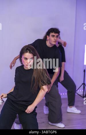 Groupe de jeunes danseurs pratiquant une chorégraphie moderne dans un studio de danse avec des néons violets Banque D'Images