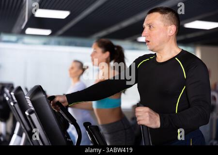 Entraînement sportif solide à l'appareil elliptique dans la salle de gym Banque D'Images