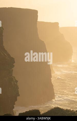Golden Hour aux falaises de Moher, avec la lumière chaude du soleil projetant une belle lueur sur les falaises. Banque D'Images