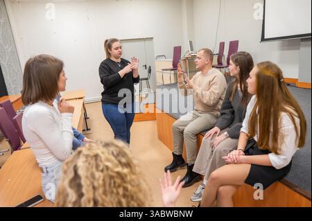 Les jeunes communiquent en langue des signes dans une salle de classe universitaire. Banque D'Images