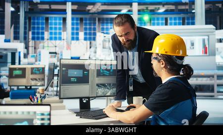 Directeur d'usine photovoltaïque montrant les corrections d'ingénieur à faire pour réparer les systèmes défectueux. Homme montrant les mises à niveau de techniciens d'usine de fabrication de panneaux solaires nécessaires pour réduire les temps d'arrêt, caméra A. Banque D'Images