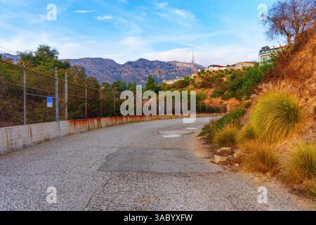 Los Angeles, Californie - 5 janvier 2025 : chemin clôturé le long des collines d'Hollywood, bordé de maisons luxueuses, de barbelés et de l'emblématique Hollywood si Banque D'Images