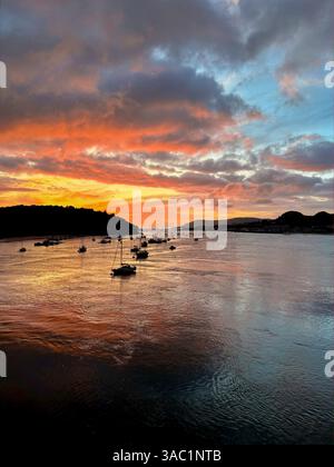 Voiliers amarrés dans l'estuaire de Conwy au coucher du soleil, avec des nuages spectaculaires et des reflets colorés sur l'eau Banque D'Images