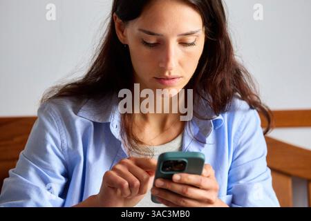 femme de 35 ans regardant un smartphone à la maison Banque D'Images
