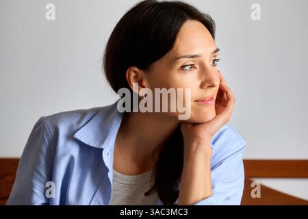 femme de 35 ans à la maison, pensant et regardant de côté Banque D'Images