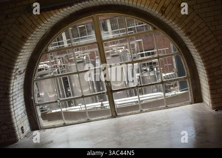 Ferme industrielle de réservoir à travers la fenêtre voûtée avec cadre en tuiles blanches Banque D'Images