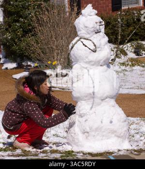 Mar 08, 2008 - Brentwood, Tennessee, USA - Une fille construisant un bonhomme de neige à Brentwood, Tennessee après une chute de neige inhabituelle en mars. Plusieurs centimètres de neige tombent sur le Tennessee alors qu'un front froid de nuit se déplace à travers la région. Le printemps comme le temps a été commun dans la région comme en témoignent les fleurs fleurissant à travers la neige en arrière-plan. (Crédit image : © Harrison McClary/ZUMA Press) Banque D'Images