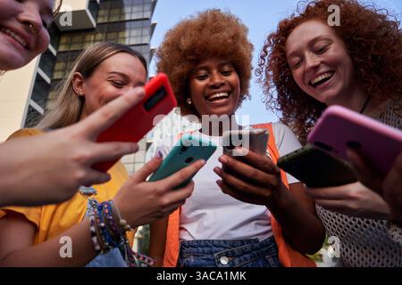 Groupe de jeunes amies multiraciales utilisant des smartphones accro à la technologie Banque D'Images