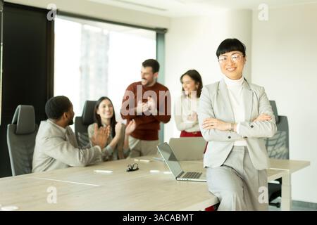Groupe de professionnels divers engagés dans des discussions animées dans un bureau ensoleillé. Une femme se tient confiante, mettant en valeur le travail d'équipe et la collaboration i. Banque D'Images