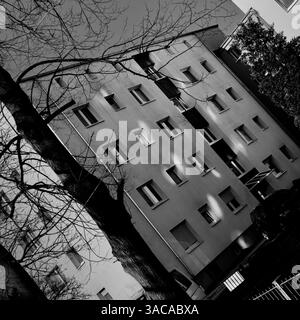 Image inclinée en noir et blanc de plusieurs points lumineux tombant sur la façade d'un bâtiment à plusieurs étages Banque D'Images