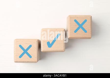Approuver ou rejeter. Cubes en bois avec des marques de contrôle et de croix sur fond blanc, vue de dessus Banque D'Images