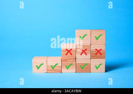 Approuver ou rejeter. Cubes en bois avec des marques de contrôle et de croix sur fond bleu clair Banque D'Images
