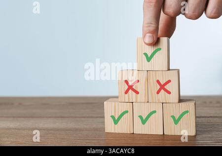Approuvé. Homme choisissant cube avec coche parmi d'autres à la table, gros plan Banque D'Images
