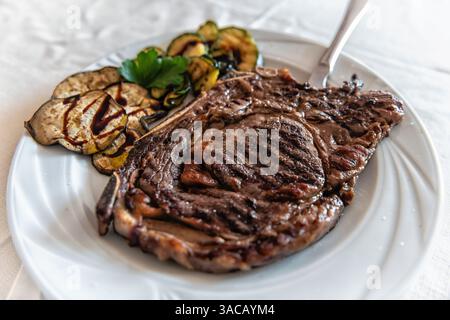 Steak de bœuf local assiette beefsteak plat traditionnel sarde en Sardaigne macro gros plan avec tranches de courgettes d'aubergines grillées sur le côté Banque D'Images