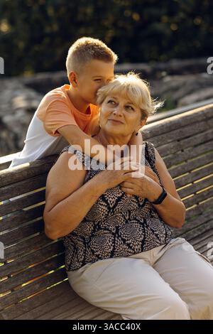 Heureuse grand-mère avec petit-fils ensemble en fauteuil roulant à l'extérieur. Banque D'Images
