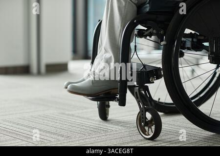 Gros plan de la personne handicapée méconnaissable dans des tons minimes, se concentrer sur les pieds en fauteuil roulant et chaussures élégantes, espace de copie Banque D'Images