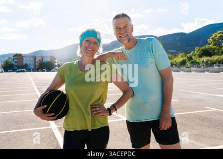 Beau couple senior heureux jouant au basket-ball et s'amusant - couple marié mature dans l'amour se lier à l'extérieur et faire du sport ensemble, concepts ab Banque D'Images