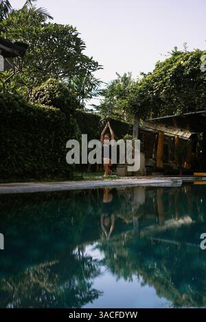 Jeune femme pratiquant le yoga au bord de la piscine Banque D'Images