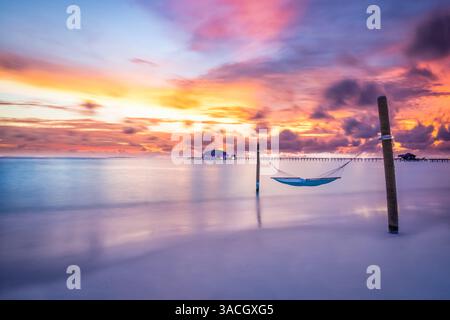 Maldives plage tropicale coucher de soleil et fond de ciel paysage d'été exotique avec hamac balançoire de plage et villas d'eau sur les vagues de la mer longue exposition Banque D'Images