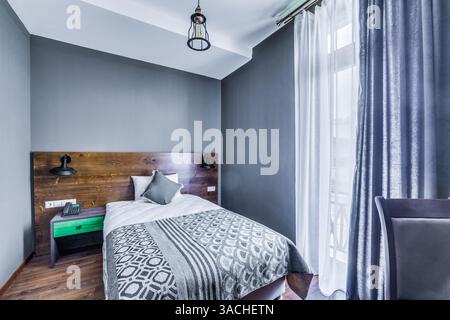 Intérieur contemporain et élégant de la chambre avec un lit confortable, élégants murs gris et éclairage moderne dans une atmosphère accueillante pour une vie détendue Banque D'Images