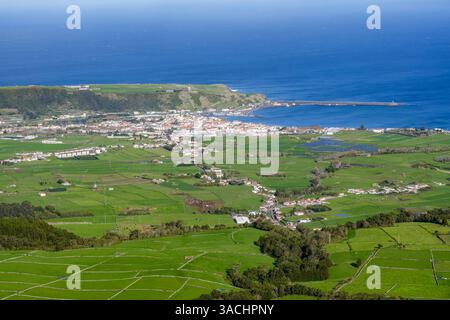 Une vue aérienne époustouflante d'une ville de Terceira, aux Açores, mettant en valeur le charme côtier de la ville au milieu de champs verdoyants et du vaste océan Atlantique. Banque D'Images