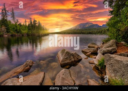 Coucher de soleil à couper le souffle pins lac rivage rocheux parfait. Incroyable aventure de randonnée dans la nature sérénité beauté inspirer. De superbes nuages de ciel éclatants Banque D'Images