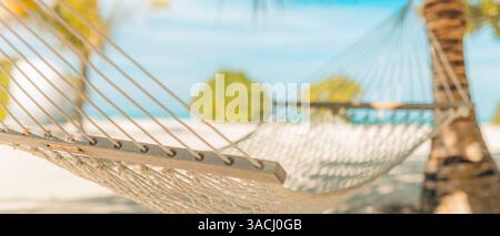En gros plan sur la plage sérénité avec hamac sous des feuilles de palmier floues. Escapades tropicales parfaites, détente côtière, retraites ensoleillées en bord de mer, vacances d'été Banque D'Images