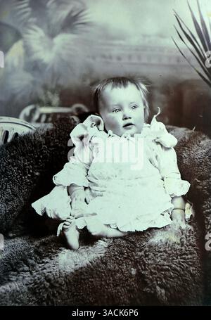 Tiré d'une photographie de portrait victorienne tardive d'une jeune fille de douze mois, probablement de Southampton, Angleterre. L'enfant est assis sur un drap de tapis et porte un frock blanc. Elle s'appelait May Blossom. La photographie provient de l'atelier de E. Mentor and Co, une entreprise fondée par Elizabeth Zilpha Mentor. La société a établi son premier studio photographique à Southampton vers 1891 et s'est ensuite étendu à d'autres endroits, notamment Brighton, Wolverhampton, Bournemouth et Southsea. Banque D'Images