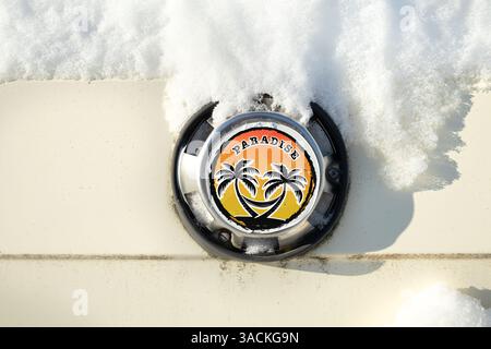 Neigé en voiture avec autocollant paradis des vacances d'été après une tempête de neige arctique. Drôle gros plan de l'évent d'air de bus vintage avec étiquette de vinyle heureux avec des paumes, Banque D'Images