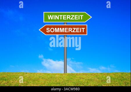 Signpost on a green meadow points in the direction of winter time and summer time Banque D'Images