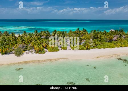 Vue aérienne de la plage des Maldives avec des eaux turquoises, des rivages de sable blanc, des villas sur l'eau et une végétation luxuriante, capturant la beauté sereine des tropiques Banque D'Images