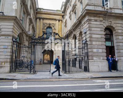 Promenades piétonnes devant les portes en fer forgé à Adams court, City of London, Royaume-Uni. Les portes comportent un écusson portant l'inscription « NPB » pour la National provincial Bank, les anciens occupants du numéro 41 avant de fusionner avec la Westminster Bank. Classé Grade II en 1977 Banque D'Images