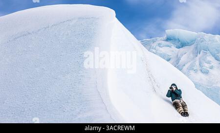 Guide Inuit anonyme avec jumelles à la recherche d'ours polaires sur la pente d'un iceberg Banque D'Images