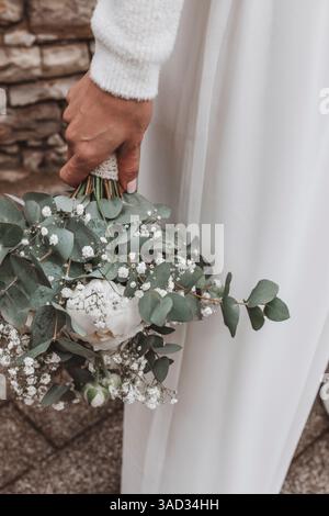 Mariée tenant décontractée son bouquet de mariée, gros plan du bouquet de mariée avec des pivoines, gypsophila et eucalyptus Banque D'Images