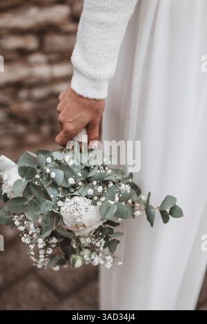 Mariée tenant décontractée son bouquet de mariée, gros plan du bouquet de mariée avec des pivoines, gypsophila et eucalyptus Banque D'Images