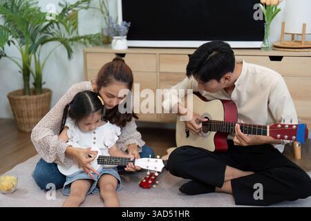 Jeu créatif et famille ensemble. Une mère guidant sa fille en jouant du ukulélé. Banque D'Images