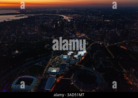 Vue aérienne du quartier du parc olympique illuminé au crépuscule avec pour toile de fond les lumières de la ville de Melbourne lors de l'Open d'Australie du Grand Chelem. Banque D'Images