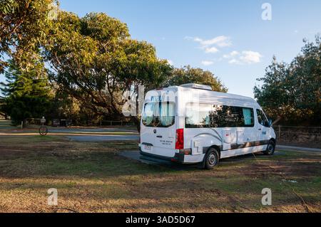 Maui Campervan garé au camping, aventure de voyage en plein air, location camping-car sous les arbres, journée ensoleillée, plage de Pambula, Australie Banque D'Images